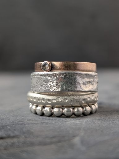 Stapelringe Mix & Match Stapelringe aus Silber und Rotgold mit verschiedenen Texturen liegen übereinander